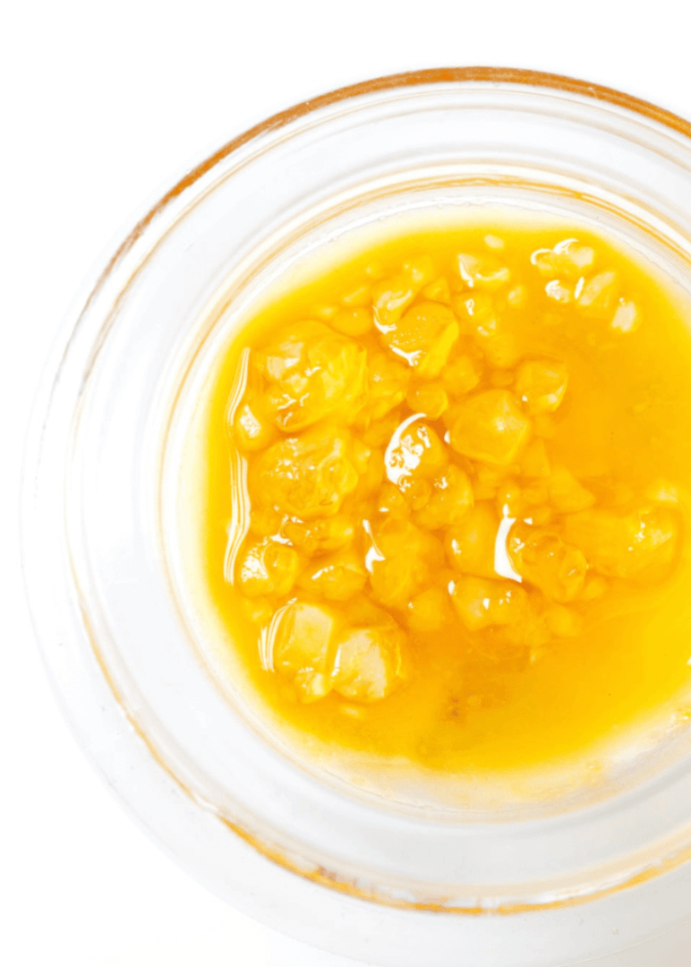 A close up shot of sauce weed extract in a glass jar. The crystallized THCa is sitting within a bed of sticky terpene-rich oil. Photo by iStock.