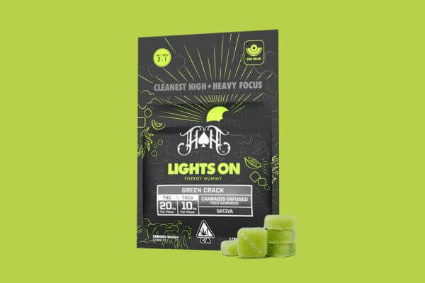 Close-up of a bag of Heavy Hitters Lights On gummies, featuring a black and green label, set against a green background.